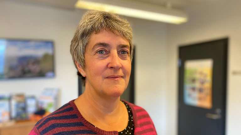 Äldre kvinna i randiga kläder på ett kontor. 