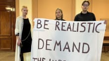 Photo shows University of Helsinki students Jonna Rajala, Isla Aarnivaara and Valtteri Harakka holding a banner at Tuesday's protest.