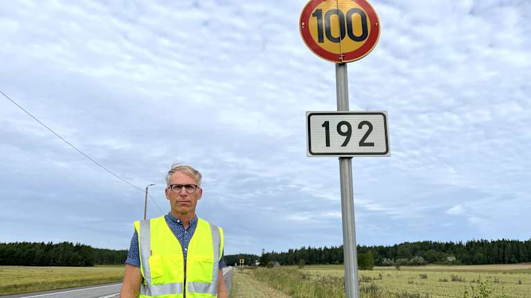 Onnettomuustutkija Jaakko Klang seisoo Kustavintiellä 100 km/h nopeusrajoitusmerkin vieressä.