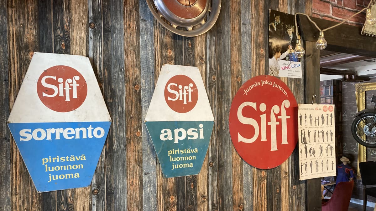 Vanhoja Siff-juomamainoksia kahvilan seinällä.