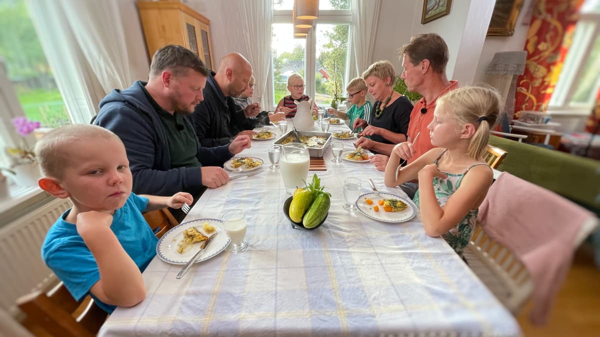 En familj sitter vid ett matbord och äter middag.