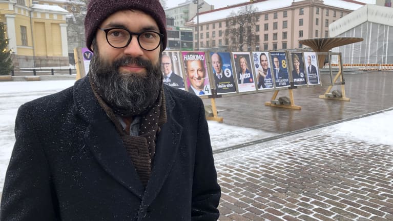 Lietolainen Santeri KIrsilä seisoo Turun kauppatorilla presidentinvaalimainostaulujen edessä. 