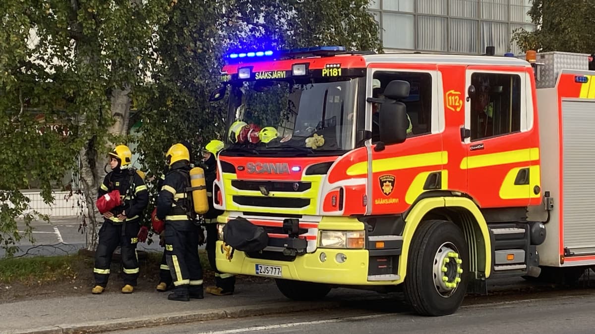 Pelastajat seisovat paloauton vieressä.
