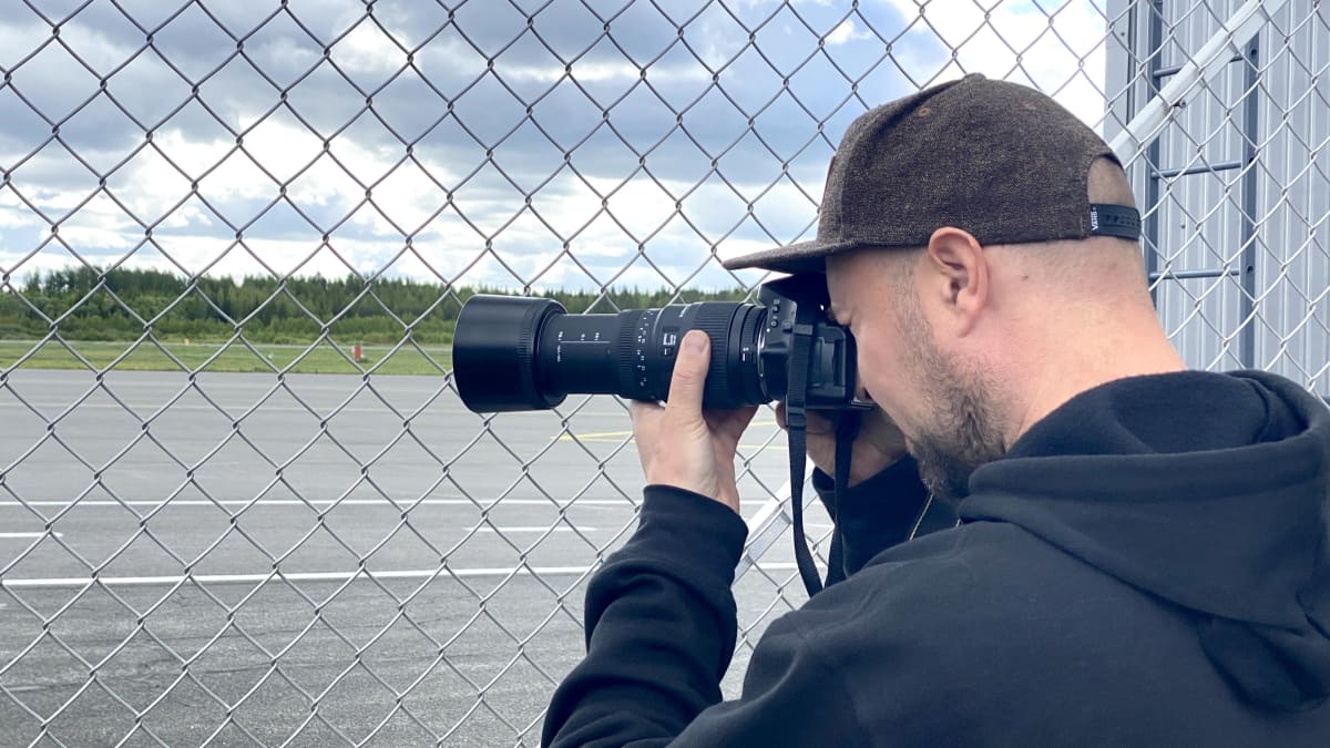 Lentokentän verkkoaidan Tommi Tapio ottaa kuvia kamerallaan.