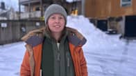 En person står ute i vintern med en orange vinterrock. 