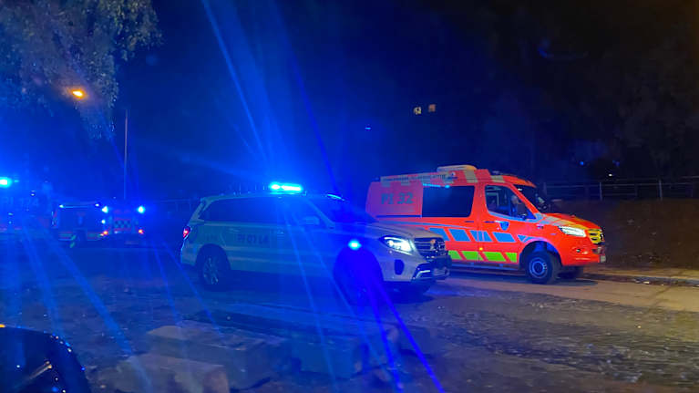 Poliisiauto, jossa vilkut päällä. Takana ambulanssi.