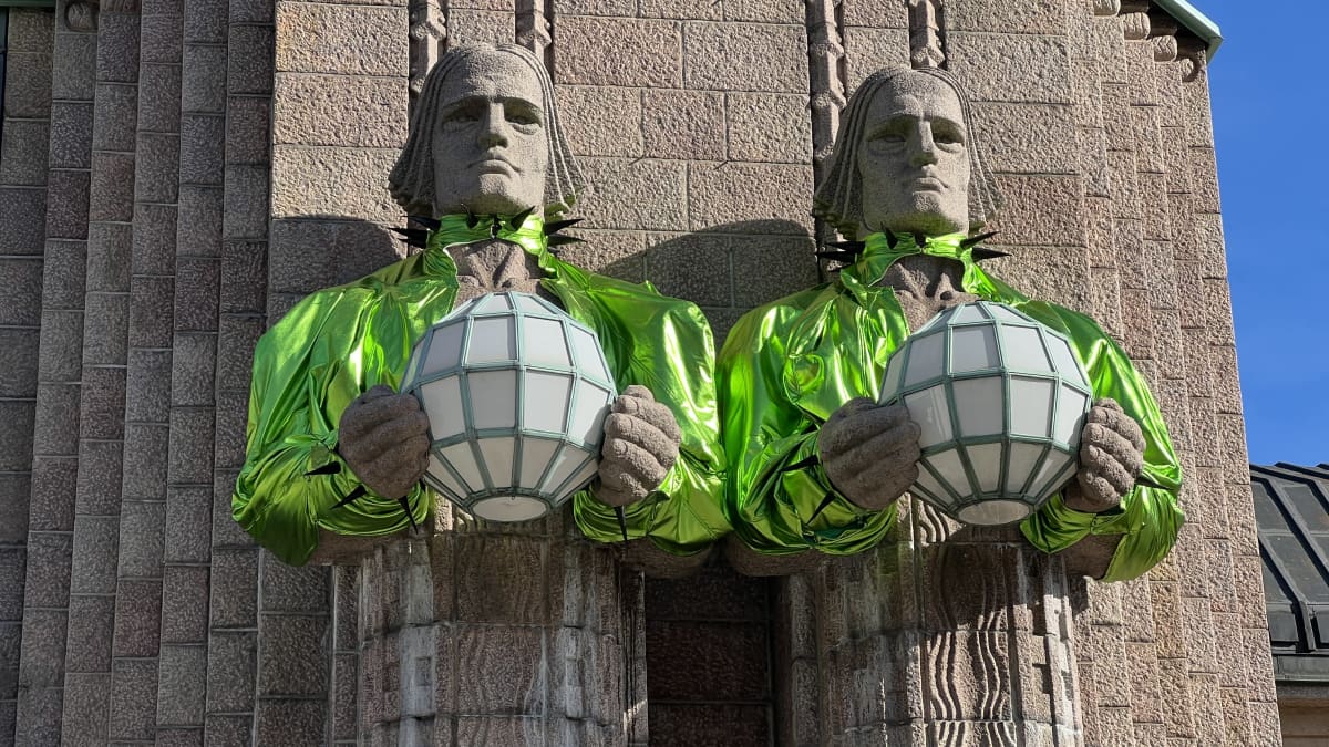 The 'Stone Men' statues at the entrance of Helsinki's Railway Station dressed in neon green boleros.