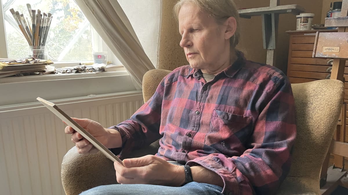 Taidemaalari Kaj Stenvall istuu nojatuolissaan ja katsoo maalaamansa teosta. 