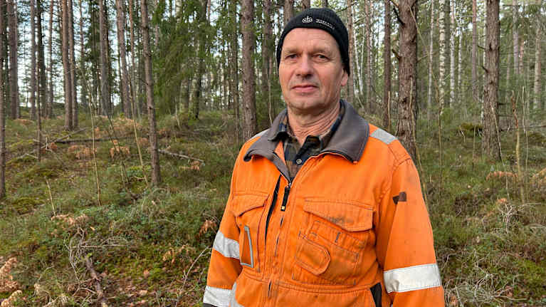 En person klädd i orange arbetskläder befinner sig i en skogsmiljö. Otto von Frenckell.