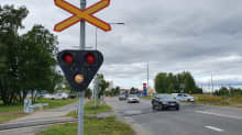 Varoitusvalopylväällä varustettu tasoristeys Kemin Eteläntiellä. Autoja on ylittämässä raiteita. Taustalla näkyy kaupungintalo.