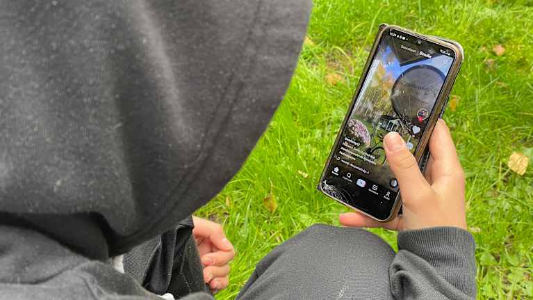 A young man is browsing TikTok videos on his mobile phone
