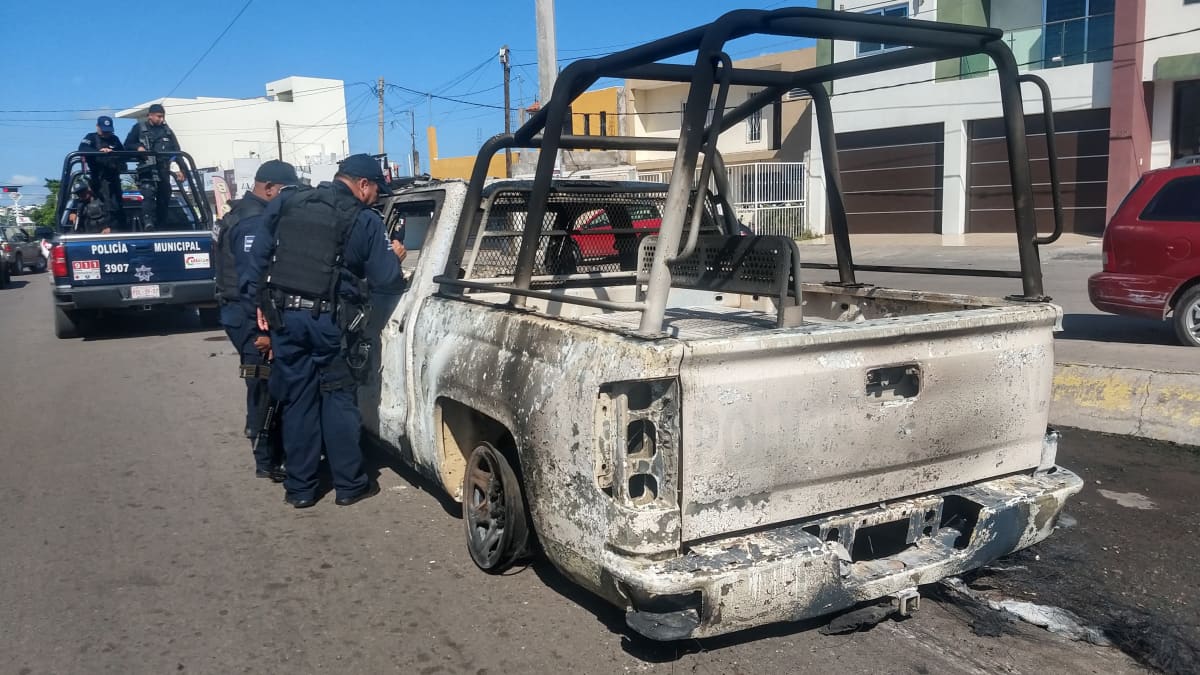 Poliisit tutkivat palanutta autoa.