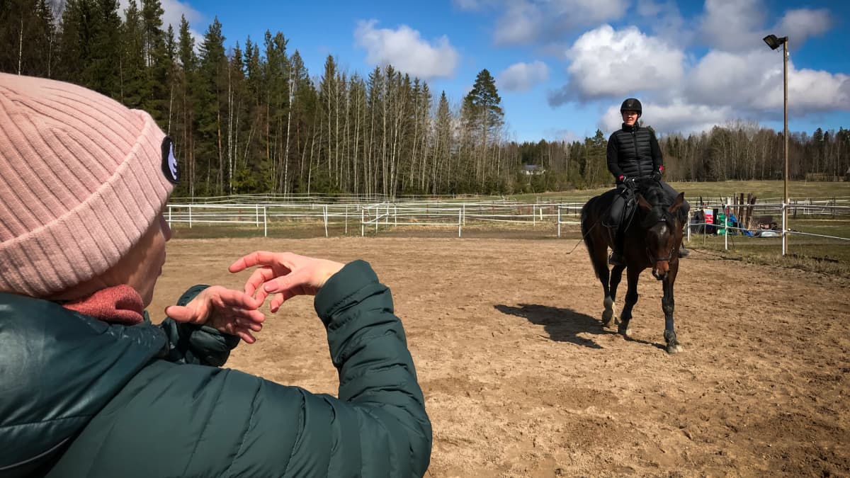 Heidi-Maria Viitanen ratsastaa ja juttelee tulkin kanssa viittoen