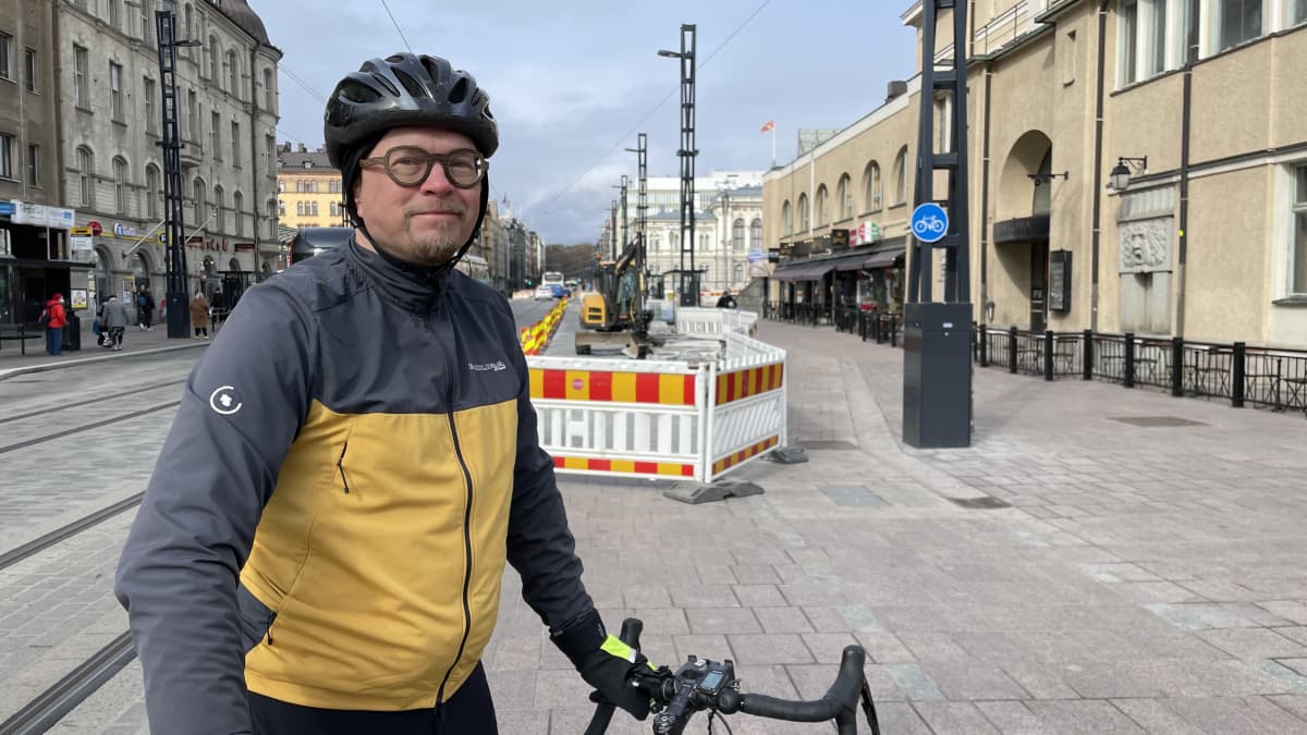 Heikki Kerppilä nojaa pyöräänsä Hämeenkadulla, taustalla näkyy Tampereen Teatteria, raatihuonetta ja Sumeliuksen taloa.