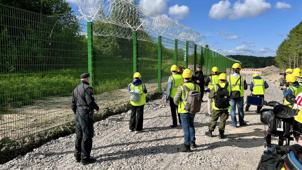 Photo shows members of the media viewing the trial border fence.