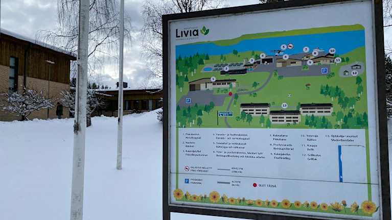 En skylt med en karta, i bakgrunden ett hus.