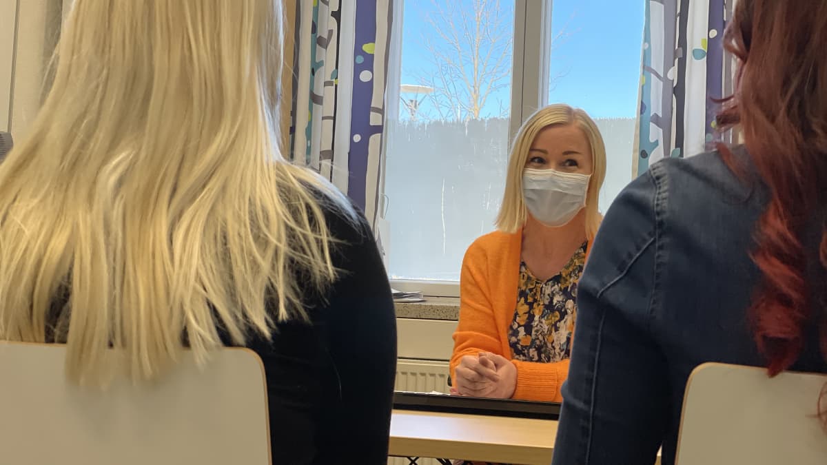 Pauliina Pöntinen juttelee kahden opiskelijan kanssa työhuoneessaan.