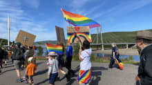 Sápmi Pride -kulkueessa Utsjoella heiluu sateenkaarilippuja ja kyltti, johon on kirjoitettu saamenkielinen teksti, joka tarkoittaa "rakkaus rakentaa perhettä".