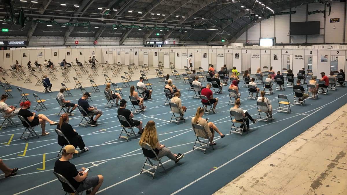 Ihmiset istuvat odottamassa rokotusvuoroaan Tampereen messu- ja urheilukeskuksen rokotuspisteessä
