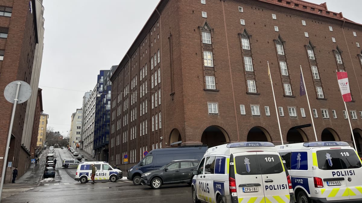 Police vehicles outside a large brick building which houses the Left Alliance party offices in Helsinki.
