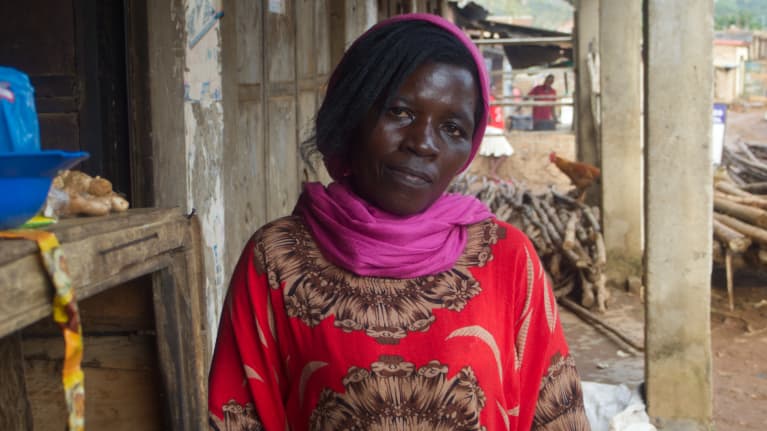 Den ugandiska kvinnan Ester Nansibirwa ser mot kameran, iklädd röda kläder och en lila sjal.