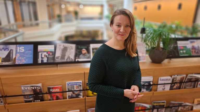 En kvinna står framför en bokhylla. 