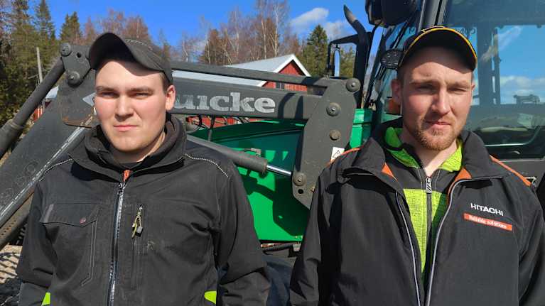 Två bröder står vid en traktor. 