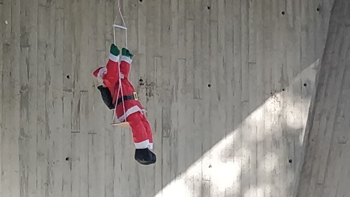 Joulupukkihahmo keinumassa Kuokkalan sillan alla, hahmo ripustettu sillan rakenteisiin.