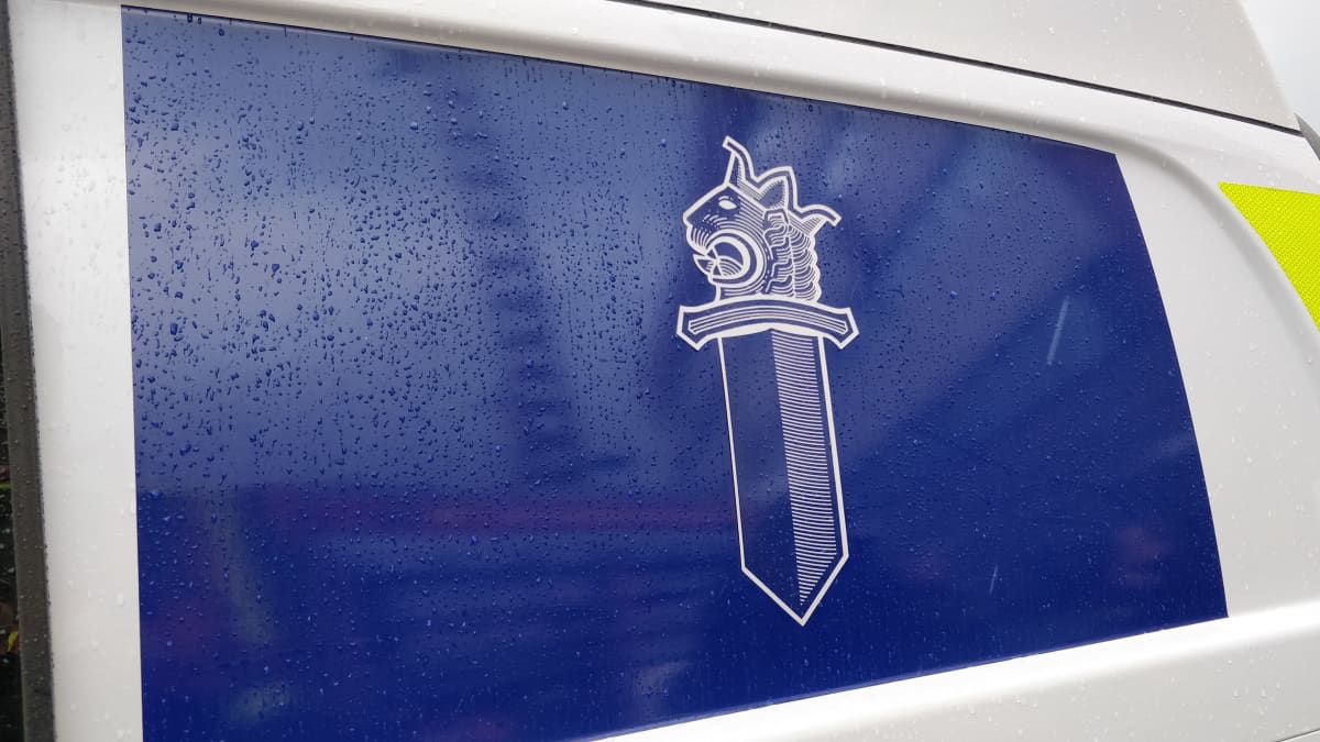 Blue panel of police van featuring an illustration of the law enforcement agency's coat of arms.