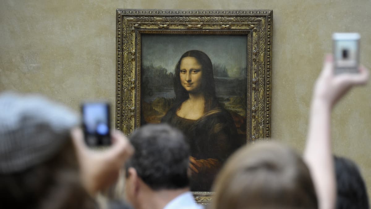 Ihmiset parveilevat Mona Lisan edessä. Osa kuvaa kännykällä.