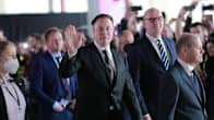 Elon Musk heiluttaa kättään, vieressä Olaf Scholz.