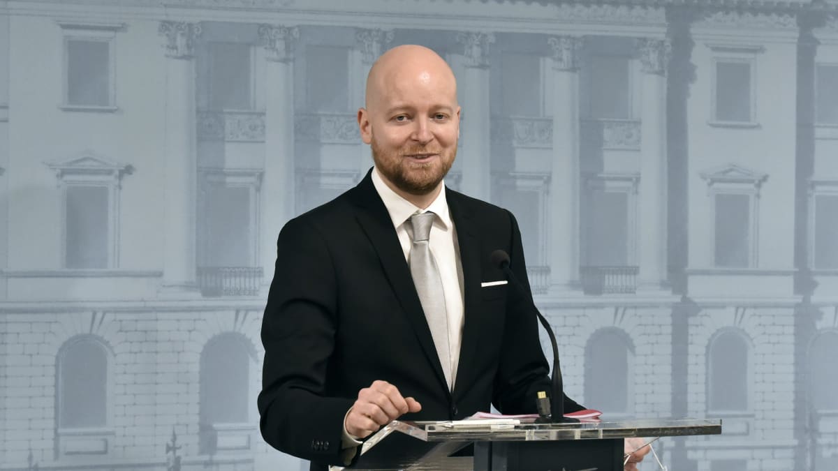 En skallig man står vid ett podium.