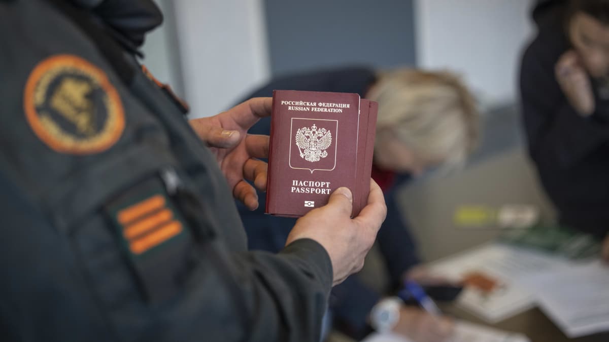 En gränskontrollant håller i ett ryskt pass.