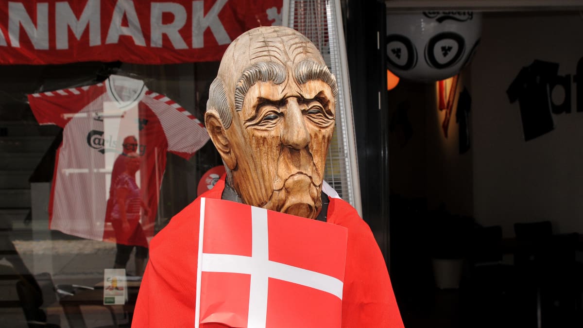 Puusta tehty mies pitelee pientä Tanskan lippua. Patsaan harteilla on Tanskan lippu.