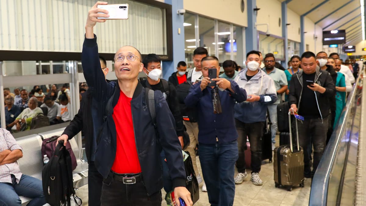 Kiinalaisia turisteja kävelee lentokentällä. Osa heistä ottaa kuvia.