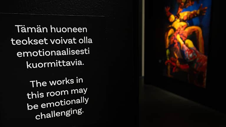 Taidenäyttelyn huoneessa varoitetaan emotionaalisesti kuormittavista teoksista.