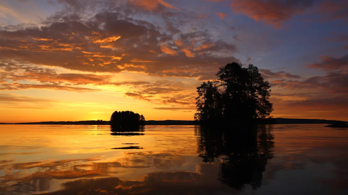 Seesteinen kesäyö Kajaanissa. Iltaruskoa ja tyyni järvi, saaria. 