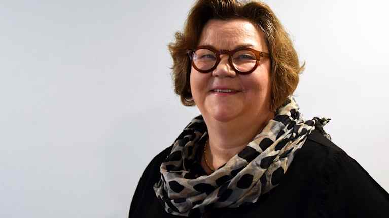 Nainen hymyilee kameralle.