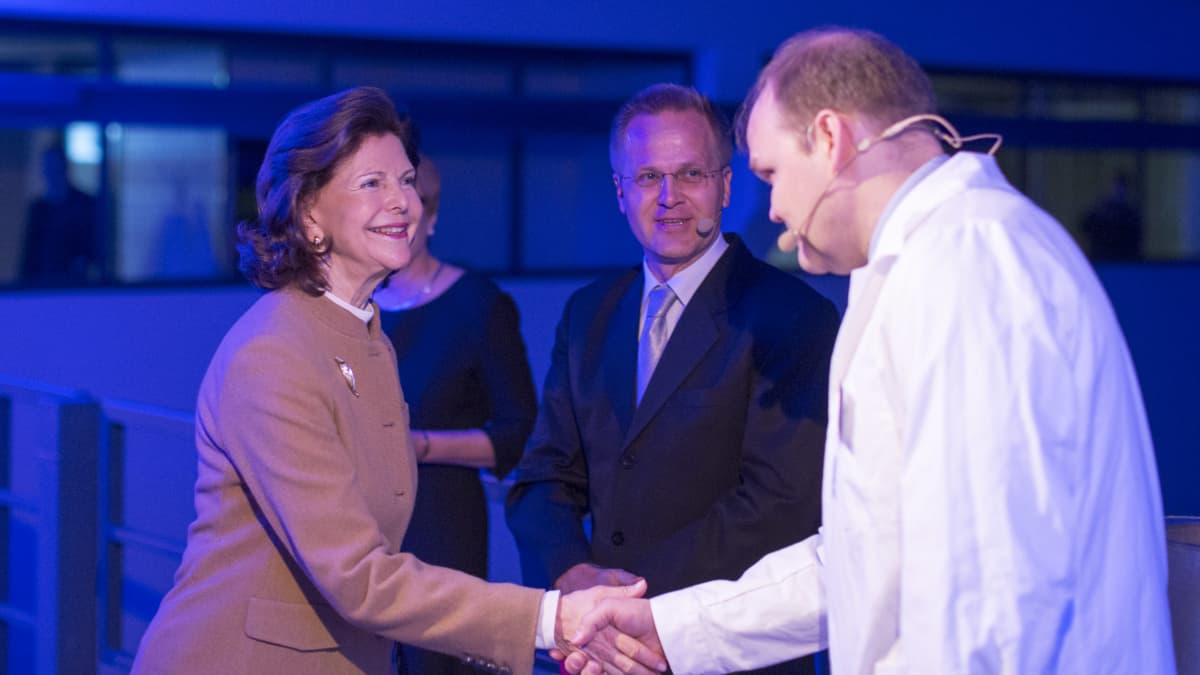 Kuningatar Silvia kättelee professori Mika Mänttäriä ja professori Mika Sillanpää katsoo heitä keskellä.