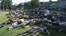 Protesters lying down on the lawn in front of Parliament House.