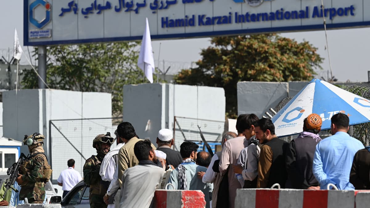 Talibankrigare övervakade en av ingångarna till flygplatsen i Kabul när anställda vid flygplatsen köade dit på lördagen. 