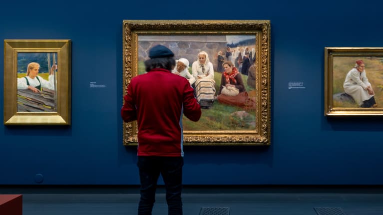 Punatakkinen henkilö katsoo Albert Edelfeltin maalausta Ateneumin taidemuseon näyttelyssä.