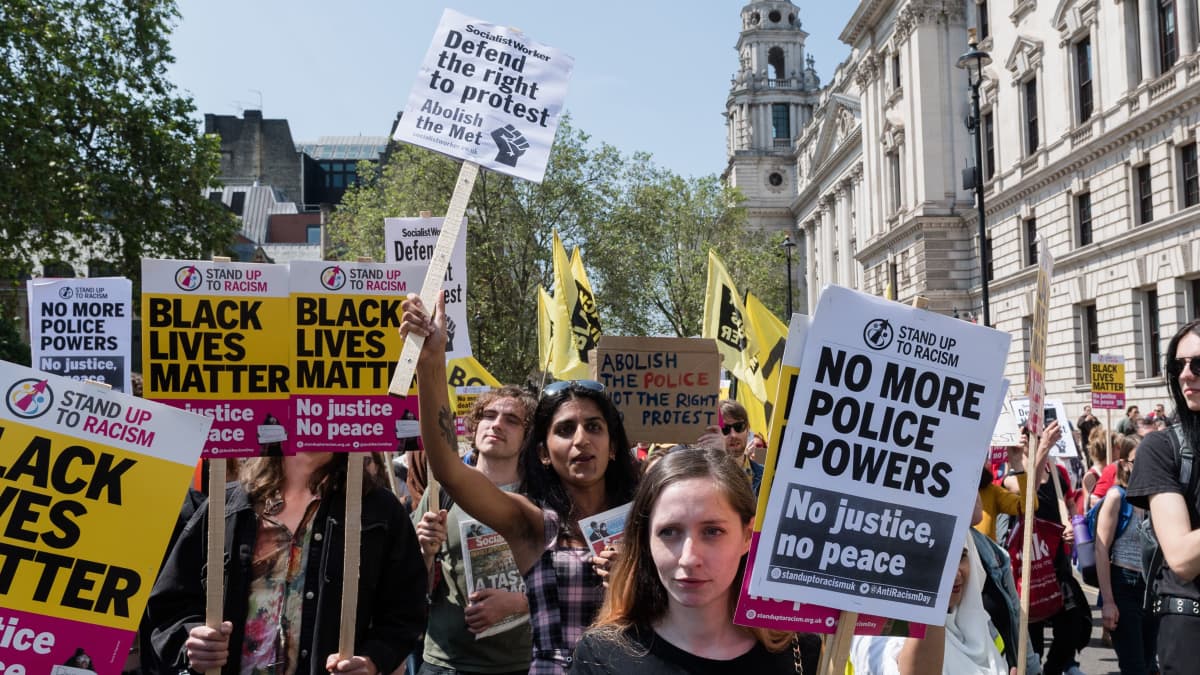 Suuri joukko mielenosoittajia pitelee kylttejä, joissa muun muassa vaaditaan Lontoon poliisin hajottamista.