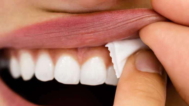 En närbild på en kvinna som sätter en snusprilla under överläppen.