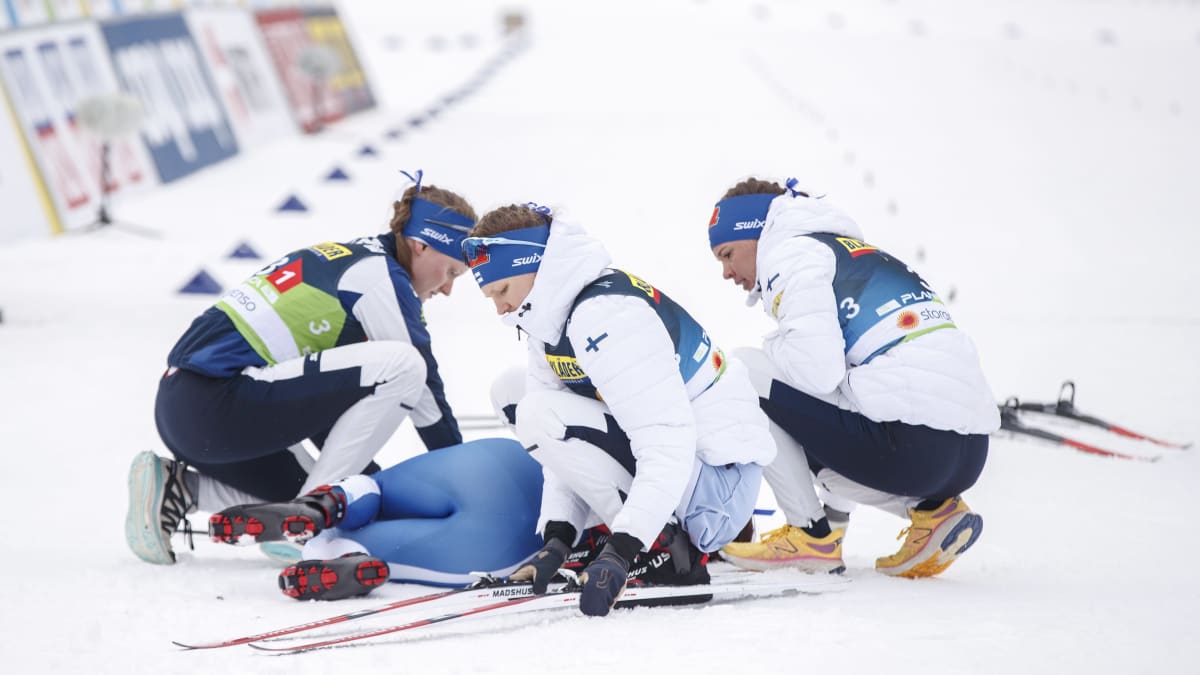 Johanna Matintalo, Eveliina Piippo ja Kerttu Niskanen auttavat maassa makaavalta Krista Pärmäkoskelta sukset pois jaloista viestin jälkeen.