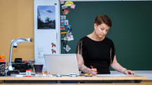 Laura Salonen katsoo papereita opettajan pöydän takana.