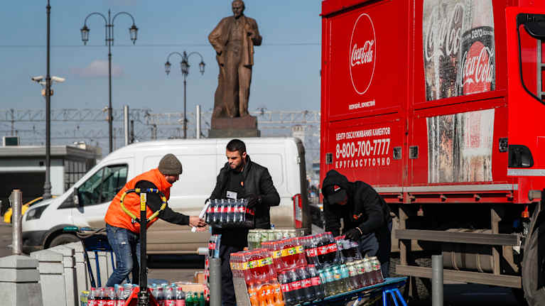  Kaksi henkilöä lastaamassa Coca-Colan tuotteita kuorma-autoon. Taustalla näkyy Leninin patsas.