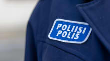 Siniseen vaatteeseen ommeltu hihamerkki, jossa lukee valkoisella poliisi ja polis.