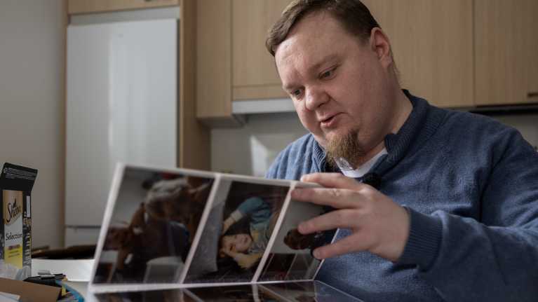 Jani-Pekka Leino katselee keittiönpöydän ääressä valokuva-albumia.
