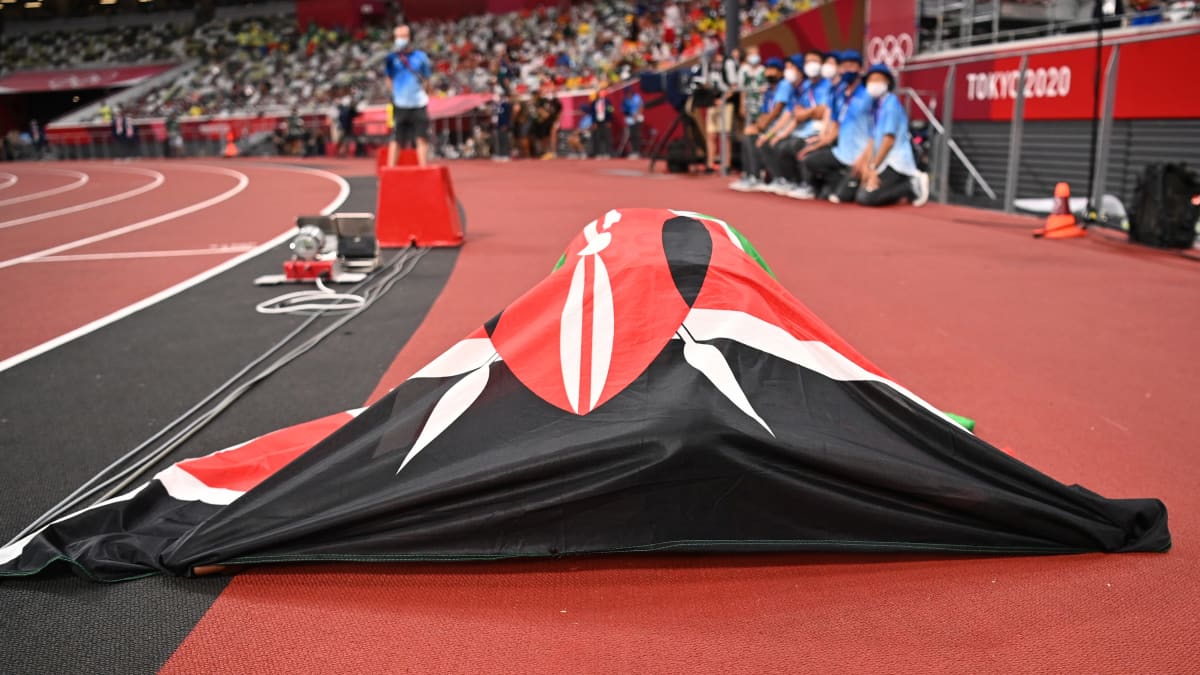 Urheilija makaa yleisurheilukentällä maassa Kenian lipun alla.